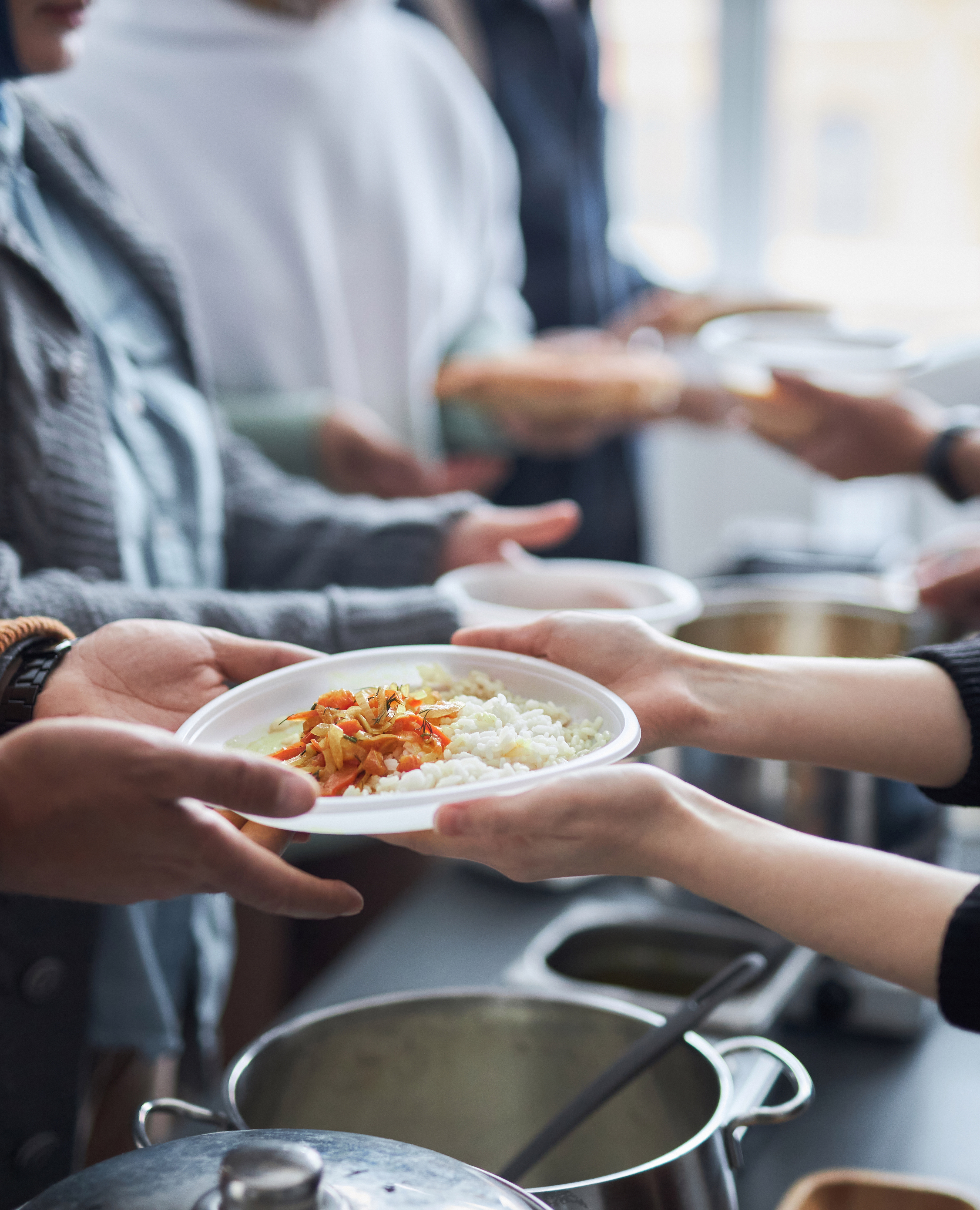 Volunteer Giving Meals to Refugees Standing in Line